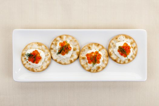 Caviar appetizer with goat cheese and crackers on white plate from above
