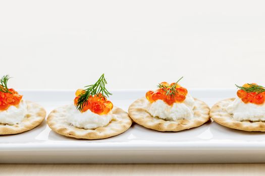 Caviar appetizer with goat cheese and crackers on white plate