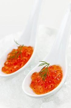 Closeup of caviar with dill garnish in two white spoons on ice