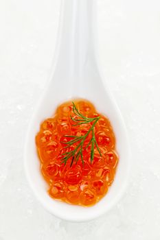 Closeup of caviar with dill garnish in white spoon on ice