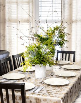 Dining table decorated for Christmas with eight place settings and evergreen centerpiece