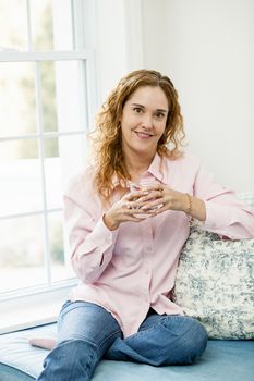 Smiling caucasian woman relaxing by window with glass of water