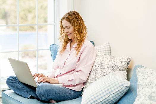 Caucasian woman using laptop computer sitting on couch at home