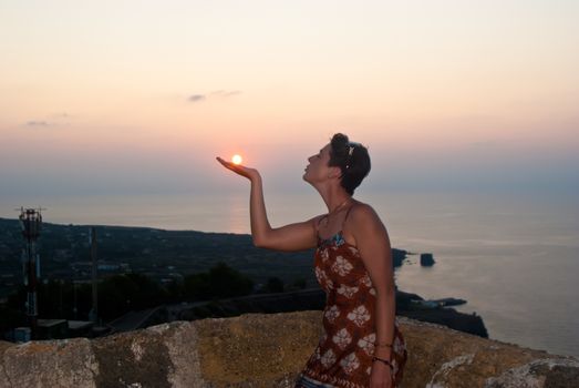Beautiful girl kisses the sun at sunset on the island of Ustica, Sicily