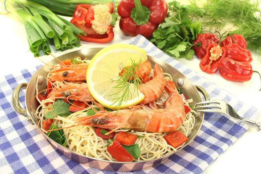 Prawns with mie noodles, lemon, bell pepper, dill and coriander on a light background