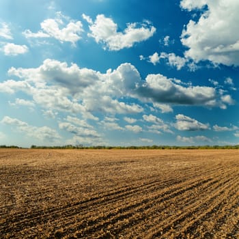 plowed field and cloudy sky in sunset