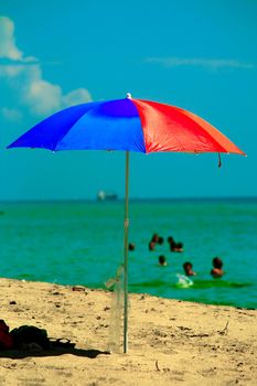 Beach umbrella on the beach with people swimming in the background, Miami, Miami-Dade County, Florida, USA