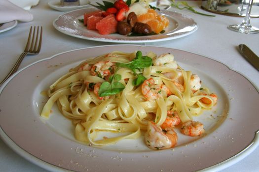 Close-up of Big shrimp pasta dish with a fruit salad dessert