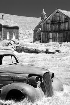 Abandoned car and historic wooden buildings in Bodie State Historic Park a Californian gold-mining ghost town.