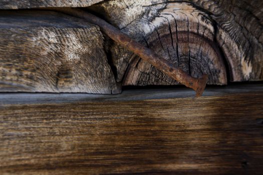 Aged and rusted iron stake is bent across cut old, dry logs. Horizontal image with copy space across bottom;  Location is a ghost town, the Fairbank Historic Site, between Elgin-Sonoita Wine country & Tombstone in southern Arizona;