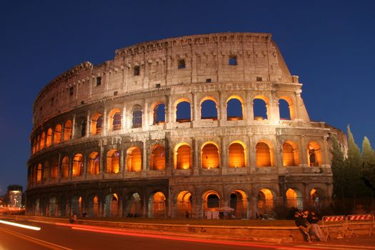 Scenic view of Coliseum or Colosseum amphitheatre in Rome with traffic light motion blurs in foreground, Italy.