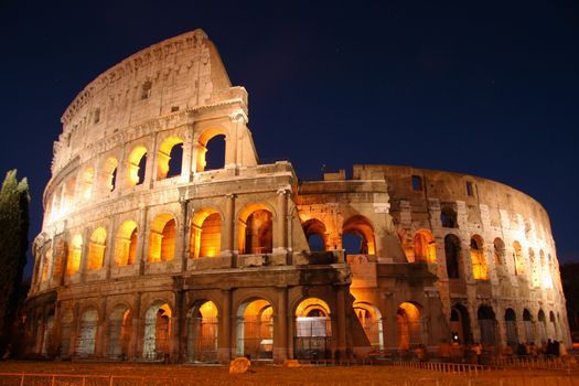 Exterior of Coliseum in Rome illuminated at night, Italy.