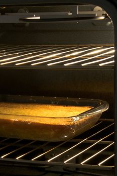 Corn cake or cornbread baked in a glass pan in an open oven with the light on.