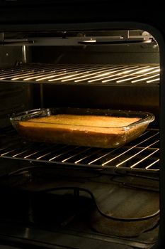 Golden corn cake in rectangular glass pan cooling in the oven after being baked.