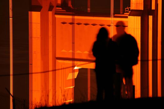 Shadow of a man and woman silhouetted on a bridge support at night