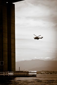 Detail of the Rio-Niteroi bridge with helicopter in background from a boat on the Guanabara bay in Rio de Janeiro, Brazil