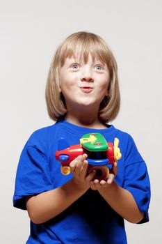 boy with long blond hair playing with toy airplane - isolated on light gray