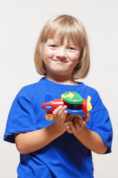 boy with long blond hair playing with toy airplane - isolated on light gray