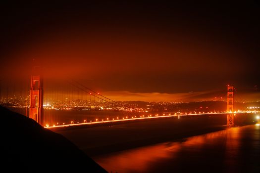 Golden Gate Bridge at night with some fog and city lights. San Francisco, United States of America.