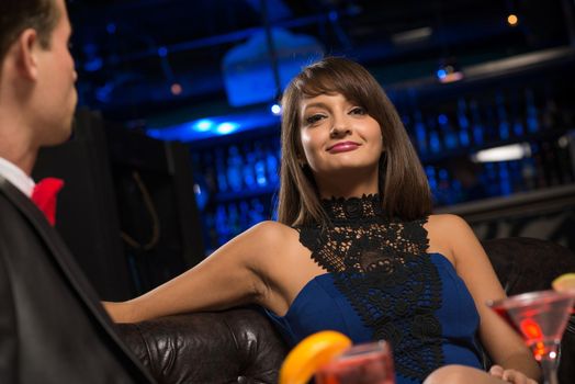 portrait of a woman in a nightclub, sitting on the couch and talking with man