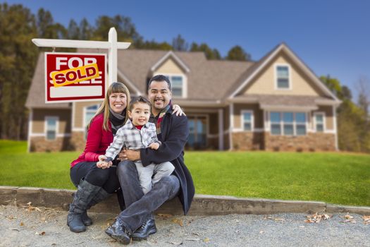 Happy Mixed Race Family in Front of Their New Home and a Sold For Sale Real Estate Sign.