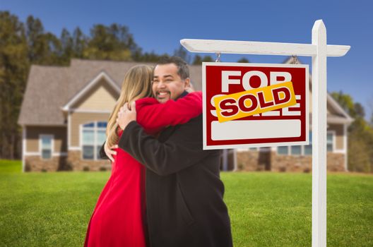 Happy Hugging Mixed Race Couple in Front of Their New House and Sold Real Estate Sign.