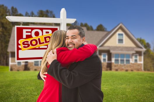 Happy Hugging Mixed Race Couple in Front of Their New House and Sold Real Estate Sign.