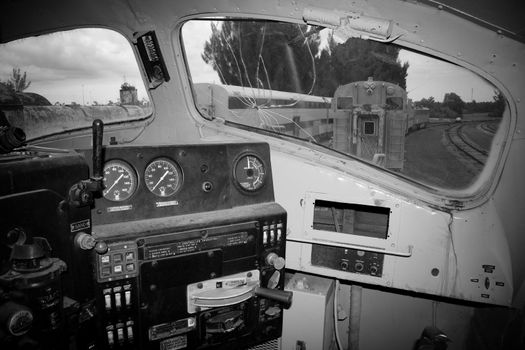 Interior of old locomotive with railway track seen through windows.