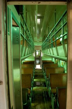 The interior of an old passenger car in a train under a green color cast.