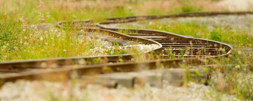 Panoramic view of old railway track in green grass.