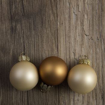 several christmas baubles bronze, brown, creme on wooden background 