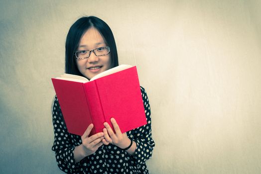 Portrait of girl reading a old red book 