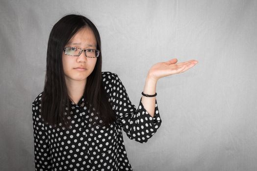 Portrait of girl holding up her hand in confusion on gray background