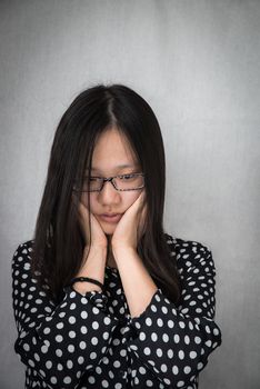 Portrait of depressed girl holding her face with gray background