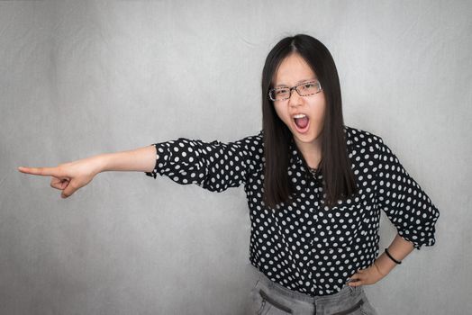Portrait of woman pointing and yelling get out on gray background