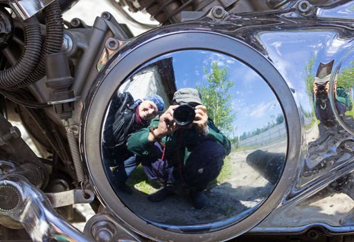 Two motorcyclists are reflected in brilliant motor motorcycle