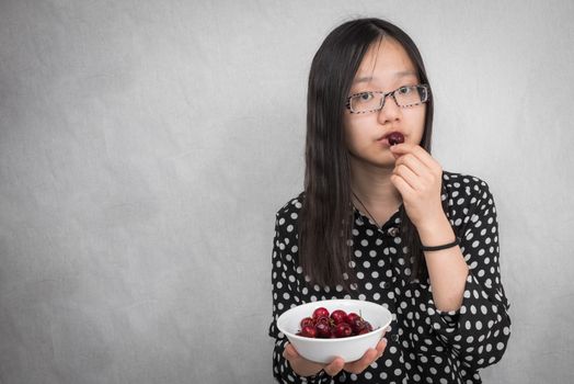 Portrait of healthy girl eating a bowl of cherry 