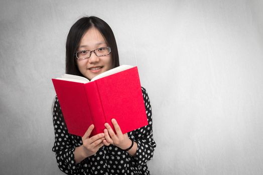 Portrait of girl reading a red book looking happy