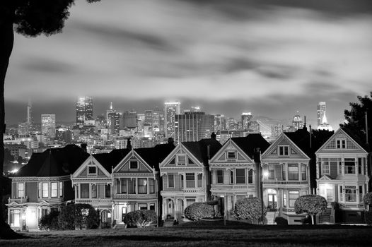 Scenic view of Victorian homes on Steiner Street at night with San Francisco city skyline in background viewed from Alamo Square Park, California, U.S.A.