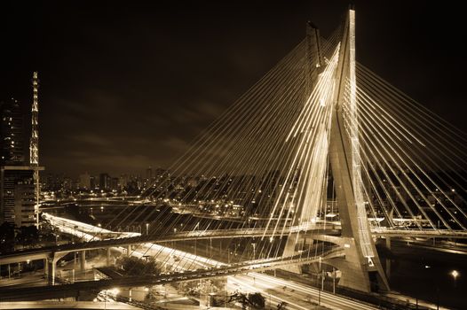 Sepia scenic view of Octavio Frias de Oliveira bridge illuminated at night over Pinheiros river in Sao Paulo, Brazil.