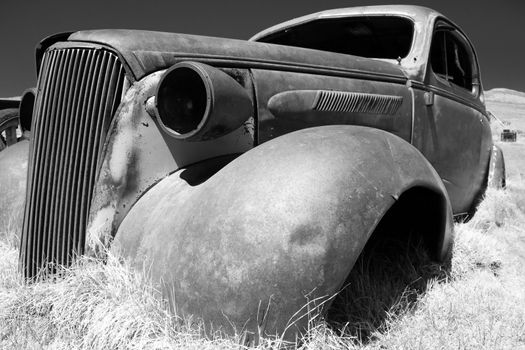 Shell of large rusting American car on rough ground in historic Bodie Park, California.