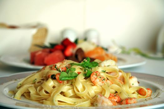 Close-up of shrimp pasta dish with a fruit salad dessert