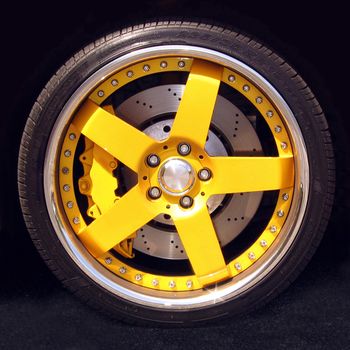 Detail of a modern yellow car wheel with tire and spokes.