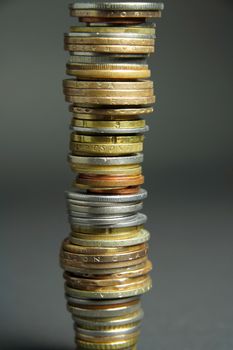 Tall stack of coins from different countries.