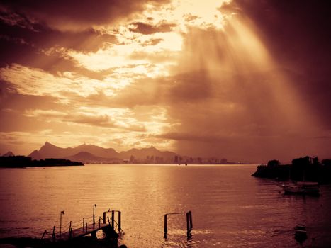 Sun rays streaming through clouds and reflecting on the water in Rio de Janeiro, Brazil.