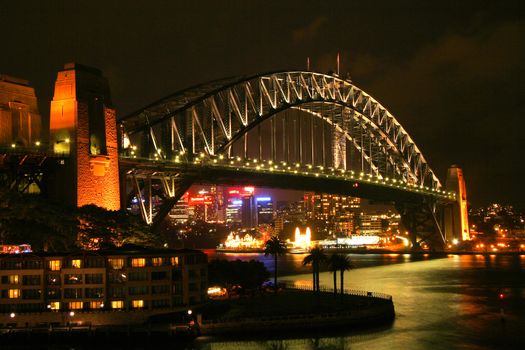 The Sydney Harbour Bridge illuminated at night with lots of city lights on the background.