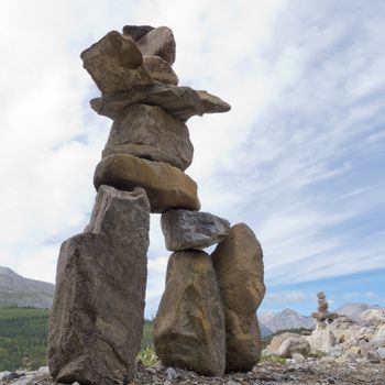 Large rocks stacked and balanced to form an Inuksuk stone landmark or cairn as a marker or monument in mountainous wilderness terrain