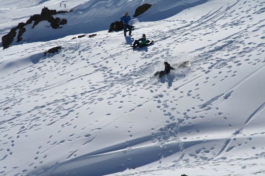 Three kids playing in the snow on a sunny day.