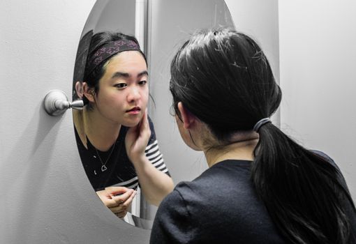 Woman looking at a mirror and putting on makeup 