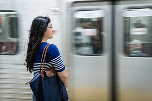 Young woman waiting at subway station with moving train